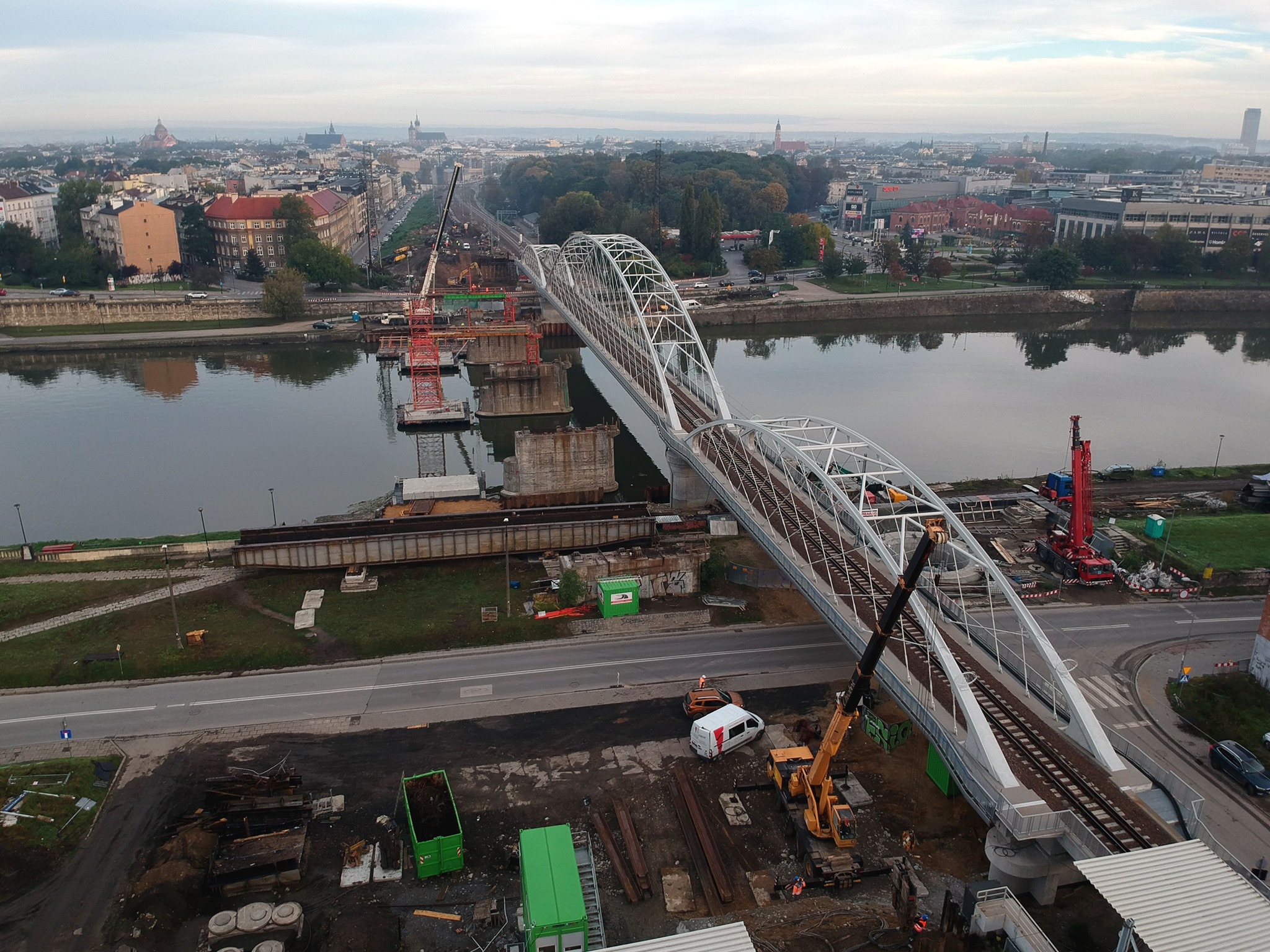 Zdjęcie z powietrza przedstawia nowy most kolejowy na Wiśle w Krakowie oraz podpory, pozostałe po demontażu starego mostu.