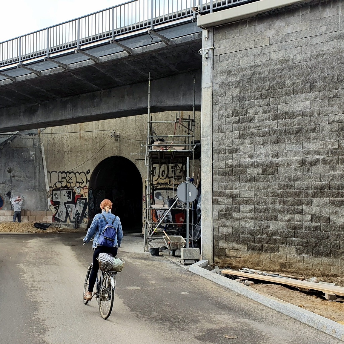 Zdjęcia przedstawiają prace asfaltowe przy wiadukcie kolejowym na ul. Miodowej w Krakowie. Wiadukt jest zamknięty dla ruchu samochodowego.