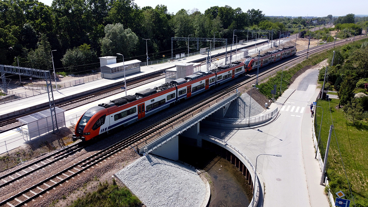 Zdjęcie nowego przystanku Kraków Złocień. Pociąg jedzie na torach przez peron.