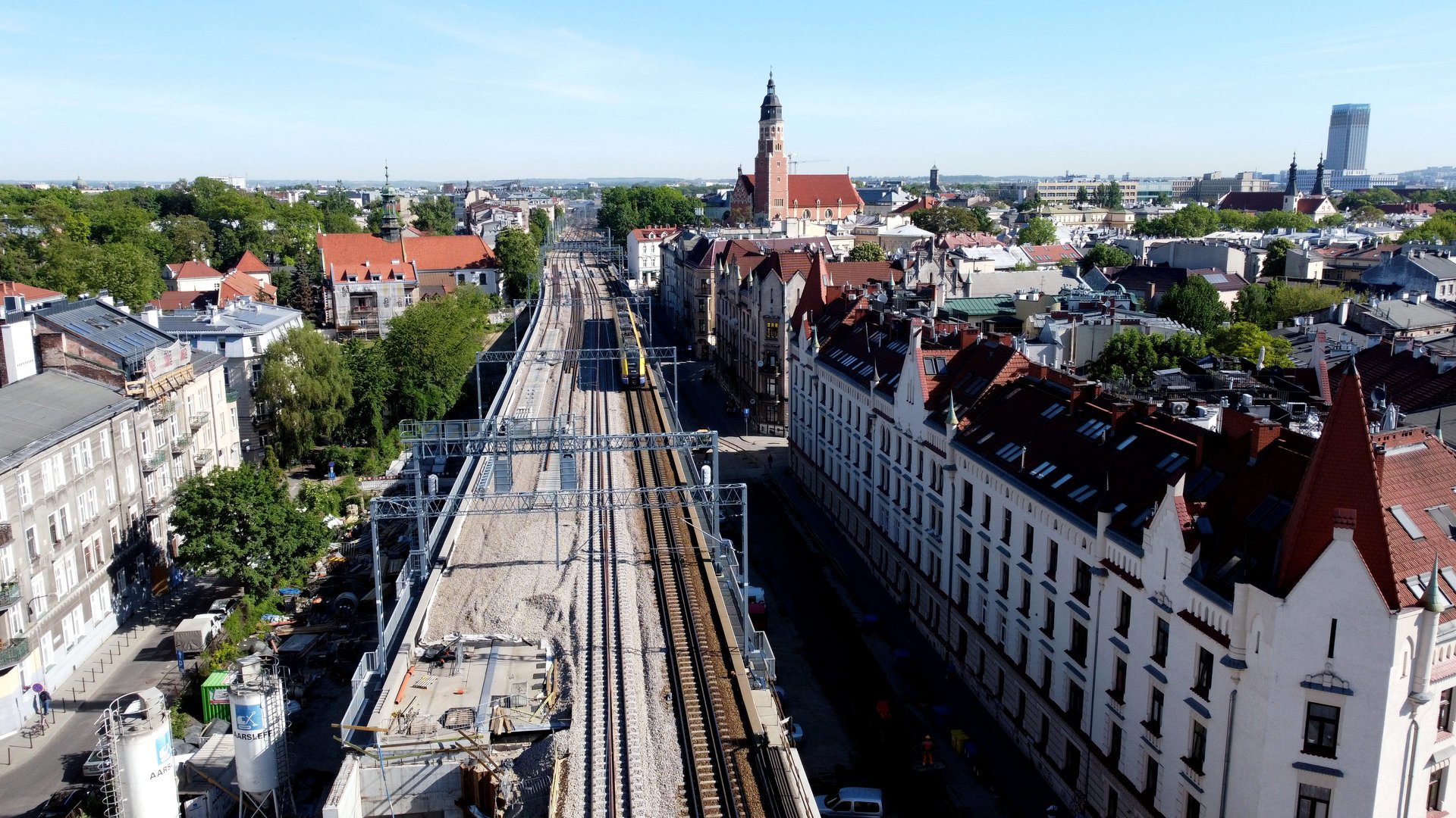 Galeria zdjęć przedstawia końcowe prace na drugim torze w Krakowie. Widoczne są pociągi sieciowe, podbijarki na stacjach i przystankach oraz pociągi na nowym moście oraz wiaduktach.