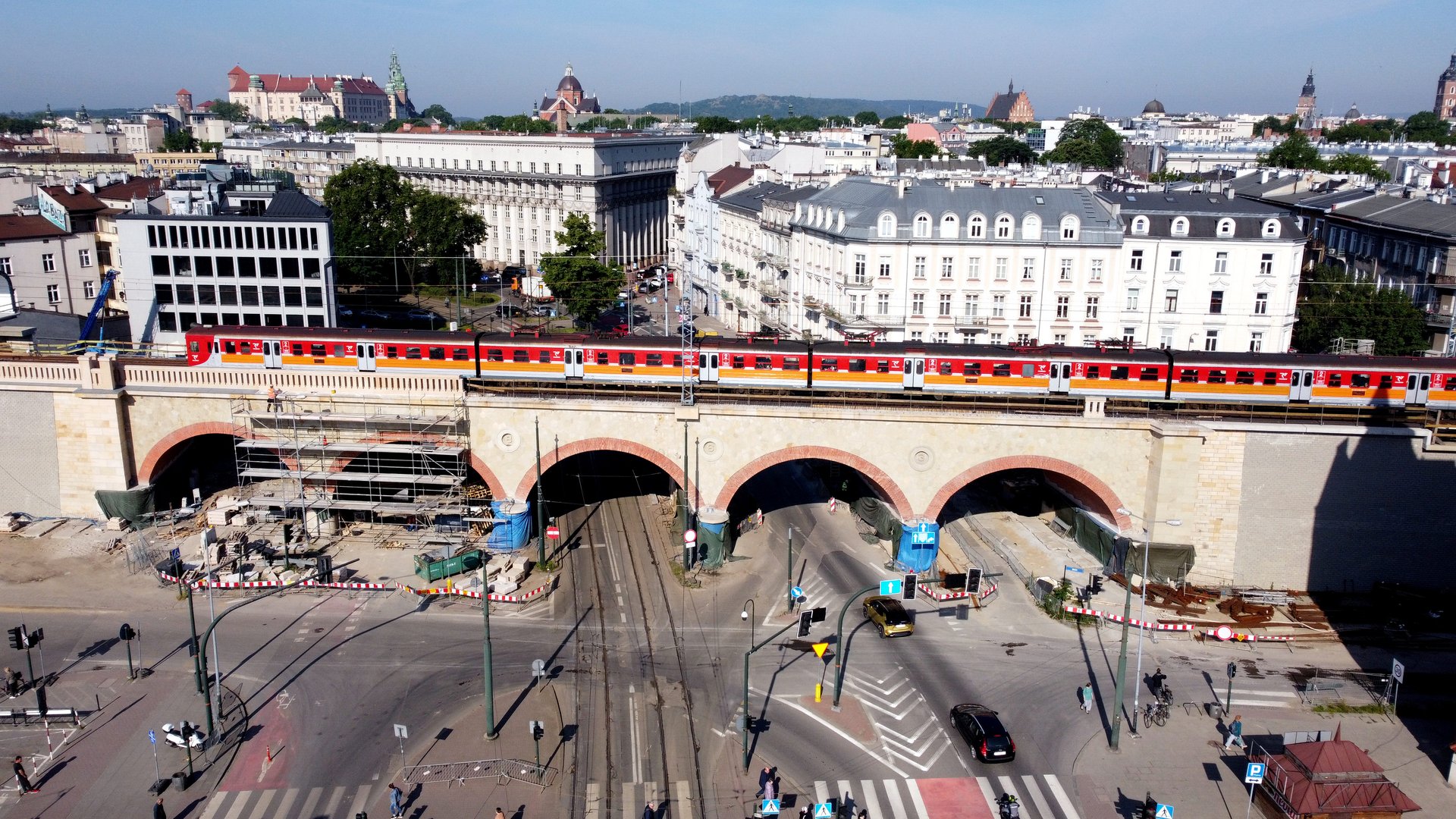 Zdjęcie przedstawia pociąg na wiadukcie na ulicy Grzegórzeckiej w Krakowie.