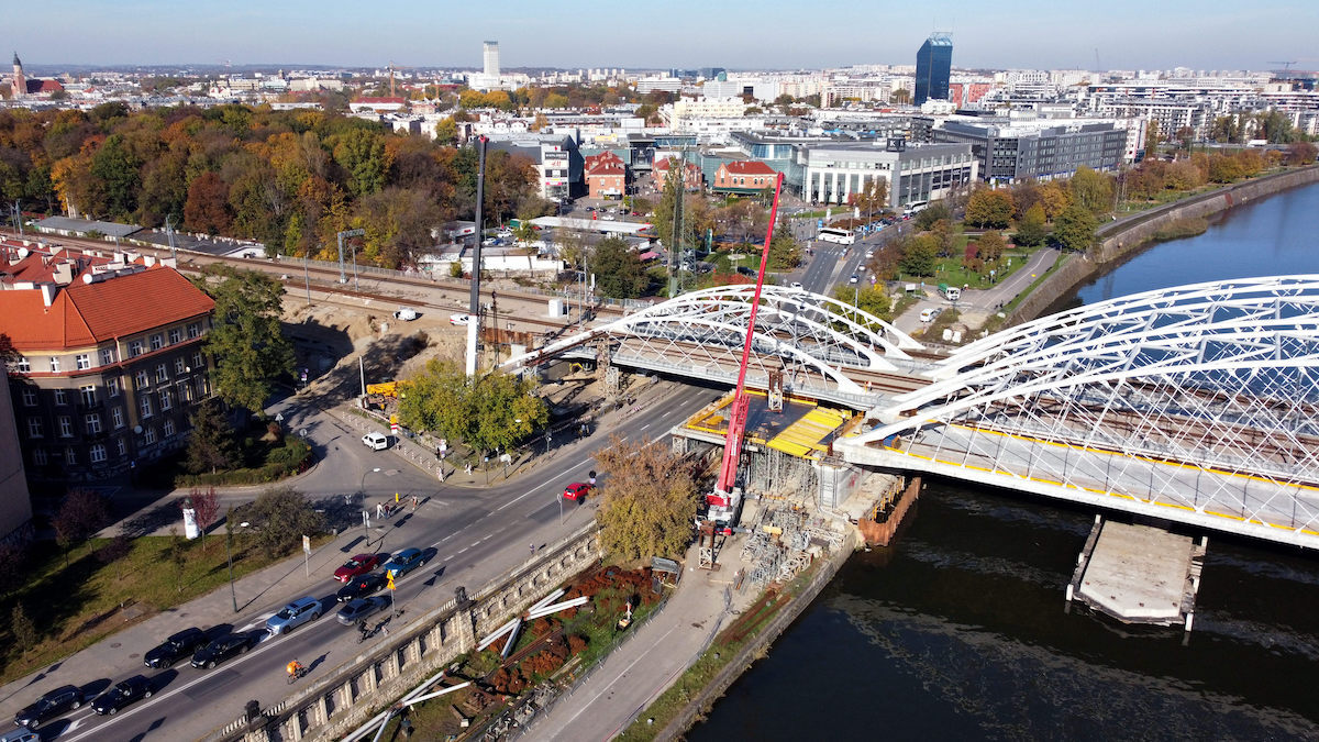 Zdjęcie przedstawia most kolejowy nad Wisłą widoczny od ulicy Podórskiej w Krakowie. Zdjęcie widoczne jest z lotu ptaka.